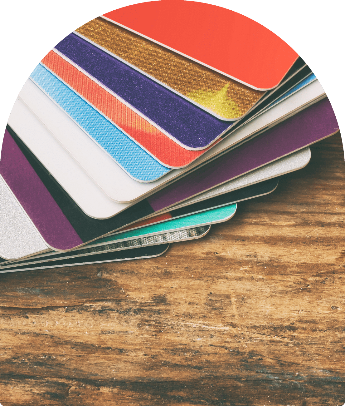 A stack of colorful laminated sheets fanned out on a wooden surface.
